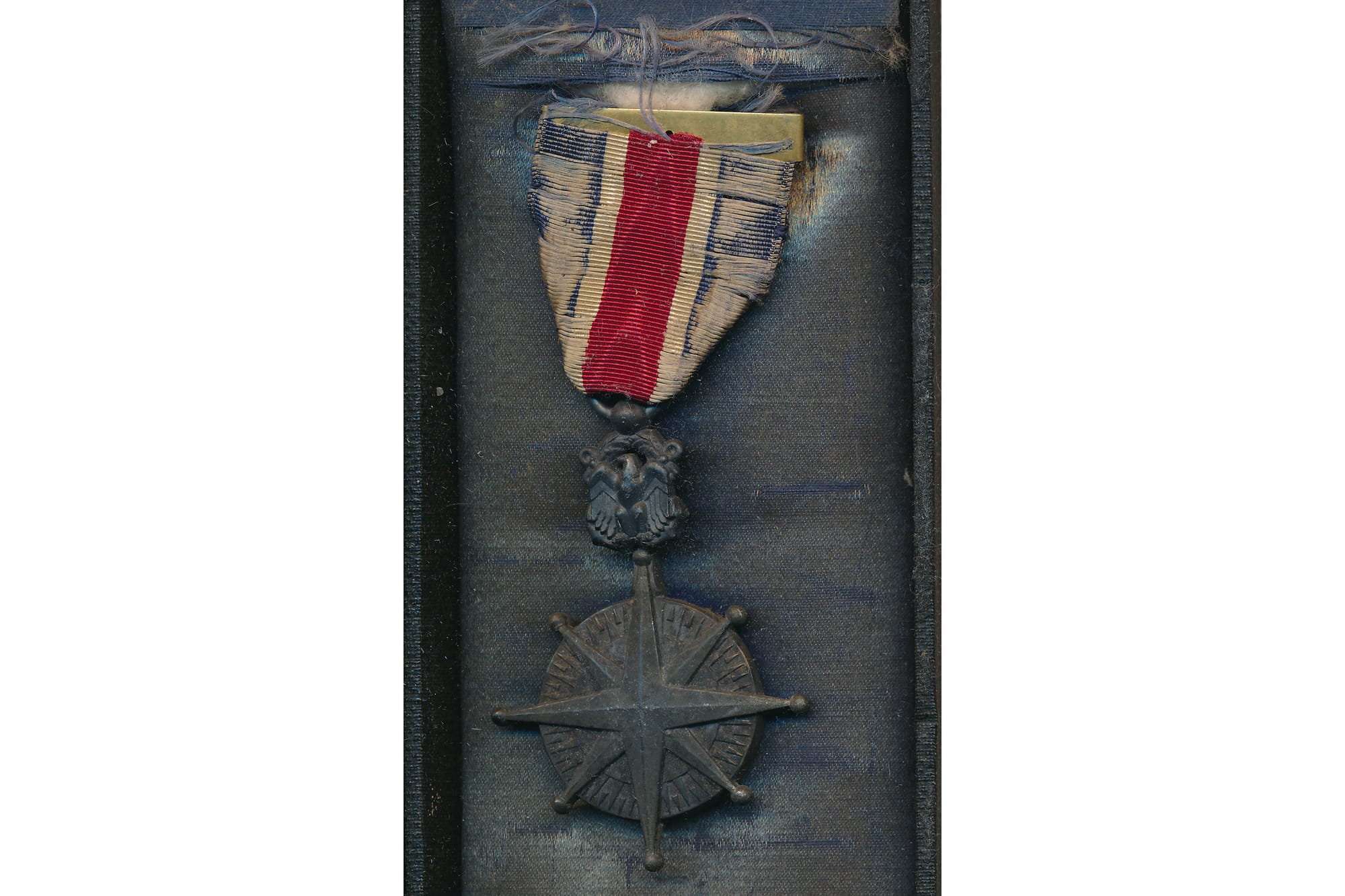 An 8-pointed star medal in a blue container