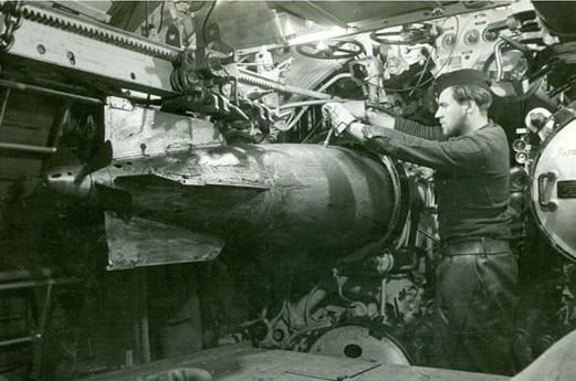 A man in a submarine works with a torpedo (black and white photo)
