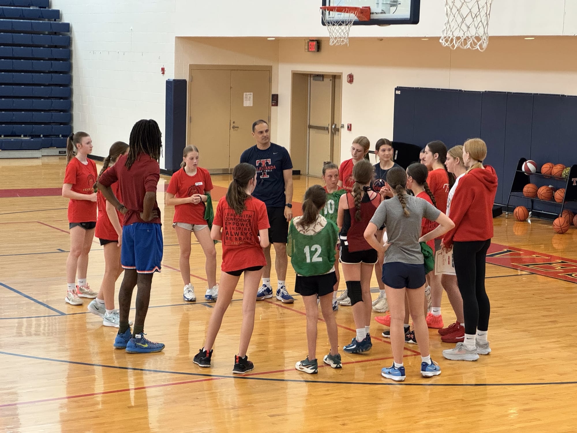 An assistant coach oversees a group discussion, while the older kids talk in a circle.