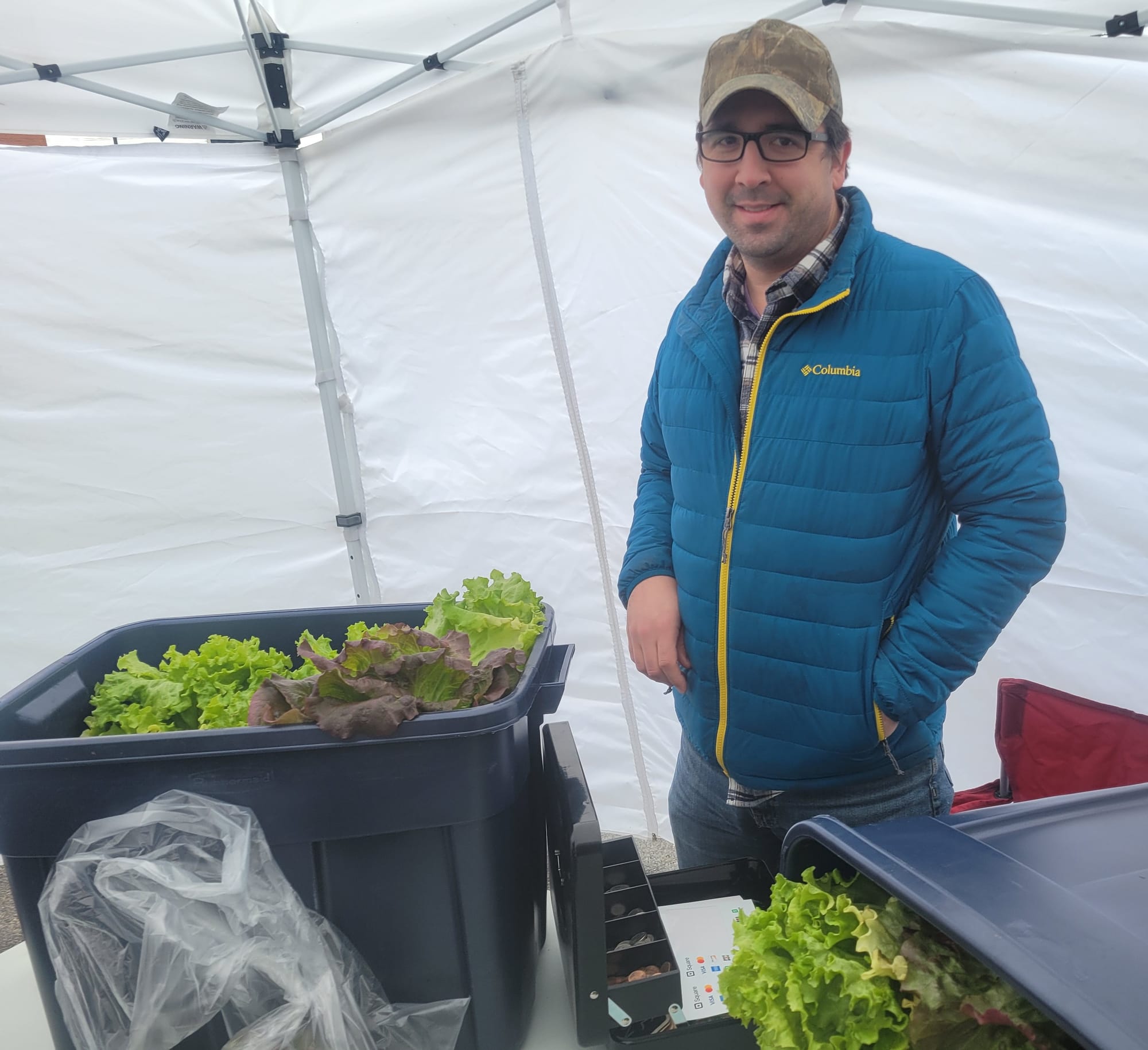 Mark Ramsey, wearing a blue jacket, stands next to a bucket of lettuce