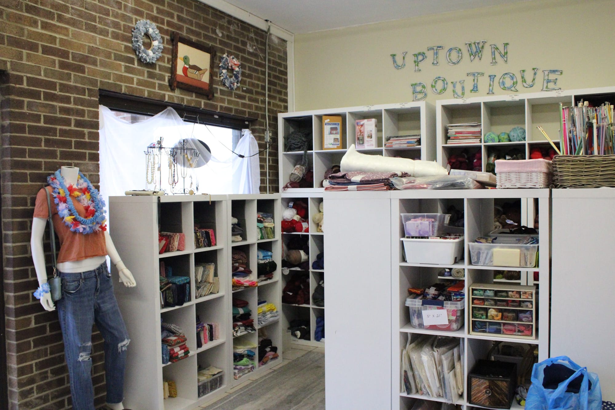 Several shelves hold different fabrics and balls of yarn.