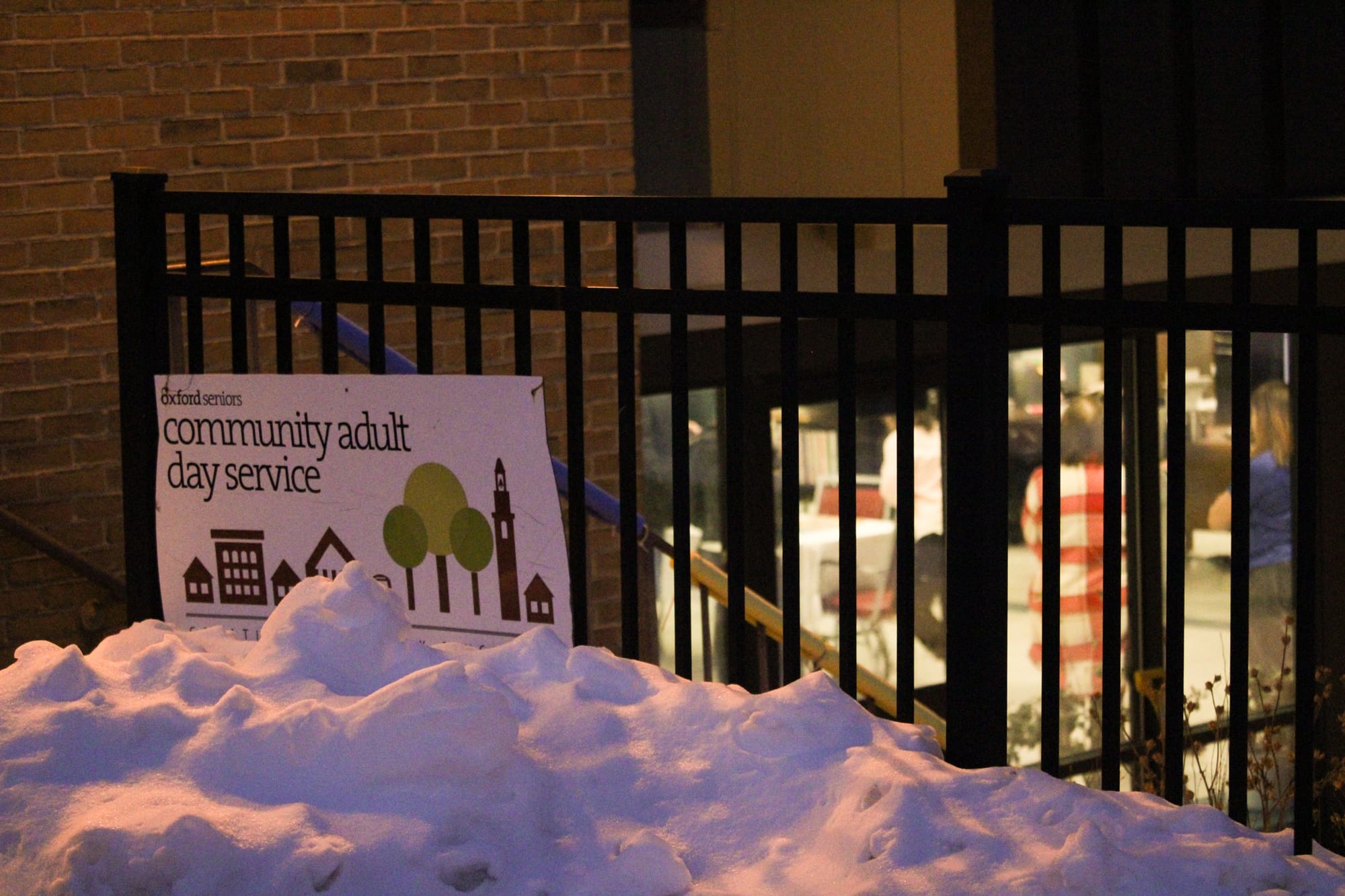 The Oxford Seniors Community Adult Day Service sign attached to a black fence