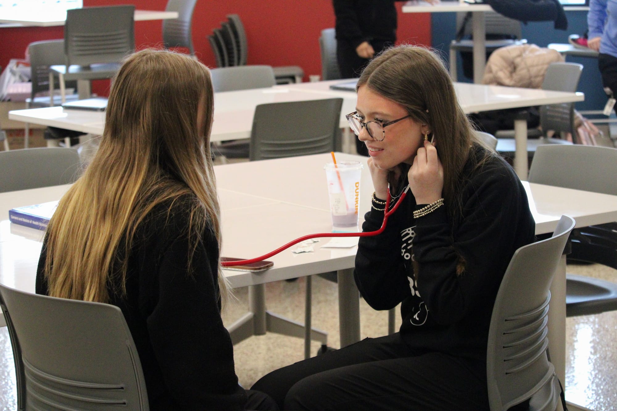 A student practices using a stethoscope during class