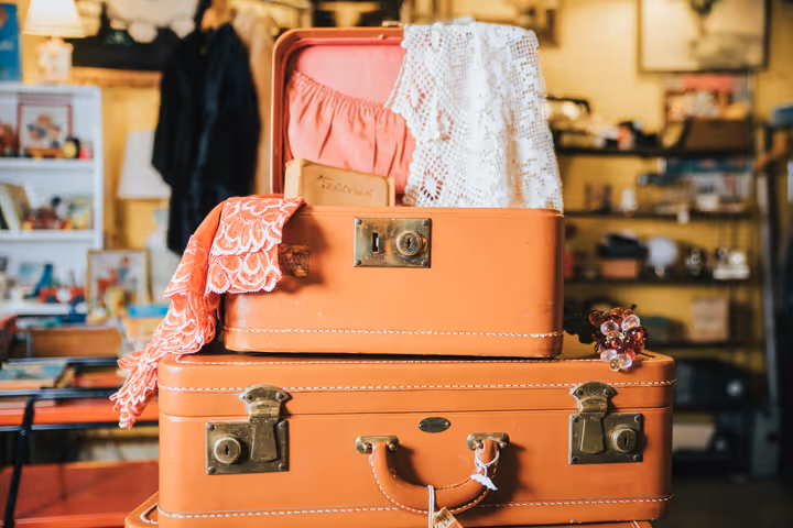 A mini brown opened suitcase rests on large suitcase.