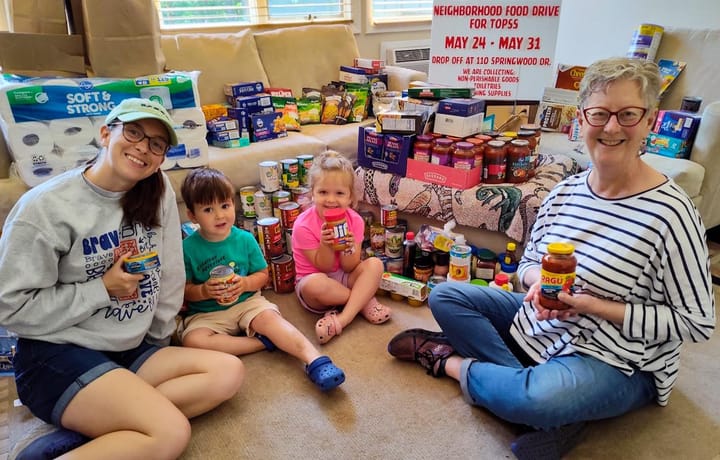 Frances Yates (far right) sits with two young children and another woman in front of food gathered for a food drive